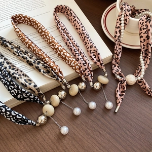 Détails de colliers en soie léopard avec perles et boules métalliques sur un bureau