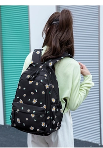 Detail of a lightweight black backpack featuring white daisy patterns and classic zipper pockets
