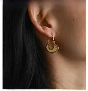 Detail of French vintage gold fan-shaped drop earrings with beaded edges on model