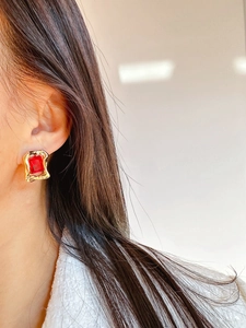 Close-up of red square gemstone earrings with irregular gold vintage textured borders
