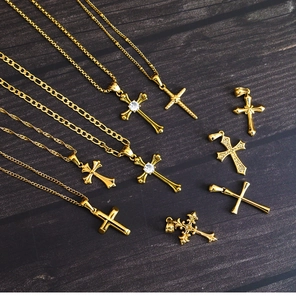 Detail of 18K gold-plated titanium steel cross pendants with CZ stones on wood