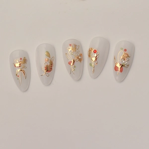 Faux ongles fleurs en cristal avec lignes dorées et perles sur forme amande