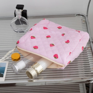 Detail of pink checkered strawberry makeup bag with quilted fabric and top handle