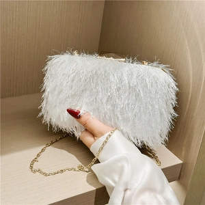 Close-up of white feather evening clutch with gold chain and elegant tassel texture