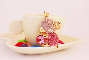 Close-up of golden sheep keychain featuring pink rhinestones holding a large pink gem