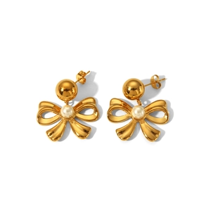 Detail of gold bow earrings with a central white pearl on a clean white background