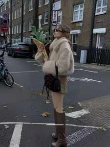 Kurzer Webpelzmantel in Beige mit braunem Rock und hohen Lederstiefeln für Wintermode