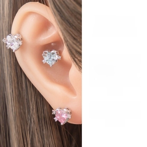 Macro shot of heart-shaped zircon earrings featuring silver prongs and delicate side stones