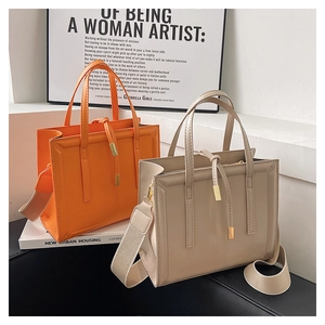 Detail of square tote bags in orange and khaki with woven straps on a stylish set