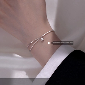 Detail view of a double-layered silver star bracelet with a 3mm star pendant on a wrist