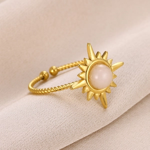 Macro detail of a sparkling golden sunflower ring with a white gemstone on beige fabric