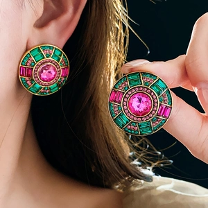 Detailed close-up of vintage round earrings with pink and green rhinestones in gold setting