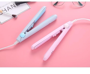 Flat lay of pink and blue mini hair straighteners on a pink decorative background