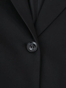 Gros plan du col en V élégant et du bouton de qualité sur une robe blazer noire ajustée