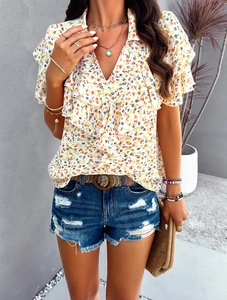 Close-up of white floral blouse with ruffle V-neck and delicate flower print detail