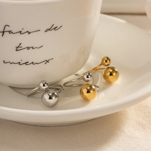 Polished gold and silver minimalist open bead rings displayed in a ceramic tea cup