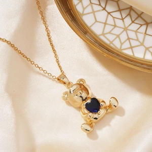 Golden bear necklace with blue heart zircon pendant on elegant silk background