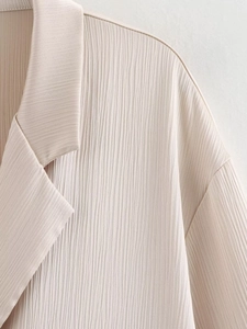 Détail du blazer plissé beige clair avec col large et texture de tissu gaufré