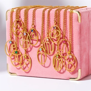 Detail of 12 zodiac necklaces with colorful stones displayed on a pink velvet jewelry box