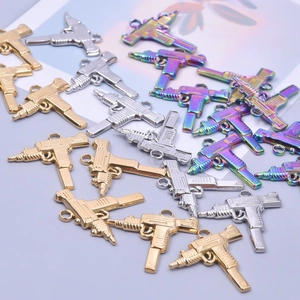 Macro view of Uzi gun charms in gold, silver, and iridescent finishes for DIY jewelry