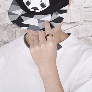 Close-up of a punk-style skull ring in gold and black finish worn by a male model