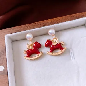 Elegant gold plated rocking horse earrings with red enamel and pearls in a jewelry box