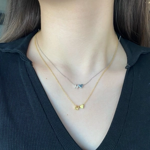 Close-up of S925 silver and gold layered necklaces with H-letter heart pendants on neck