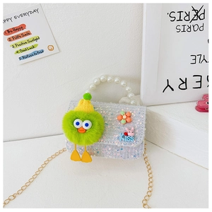 Detail of sequin kids handbag featuring pearl handle and cute monster plush charm