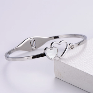 Detail of silver heart-shaped shell bangle with sparkling zircon stone on stone prop