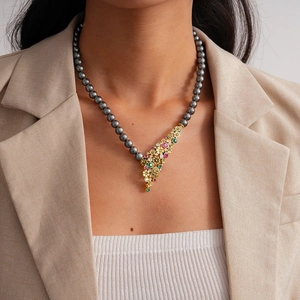 Detailed close-up of vintage flower pendant with pearls worn over a beige blazer