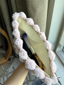 Detail of pink plush pom-pom makeup bag showing spacious canvas interior and soft texture