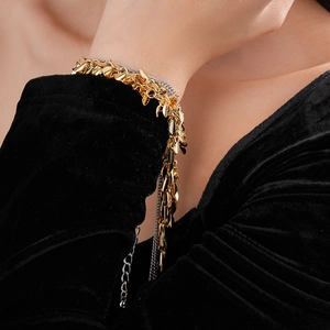 Close-up of golden wheat leaf tassel bracelet worn on wrist over black velvet fabric