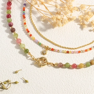 Detail of multi-layered rainbow gemstone necklace with golden star pendant on a beige surface