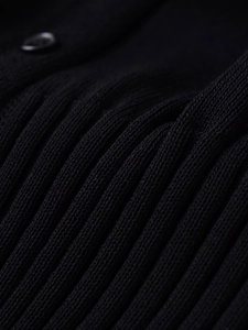 Macro view of black ribbed knit fabric detail with a matching round button closure