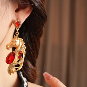 Nahaufnahme von Vintage-Pferdekopf-Ohrringen in Gold mit roten Edelsteinen und Strasssteinen