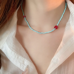Close-up of blue and red beaded necklace with star pendant worn on a model neckline
