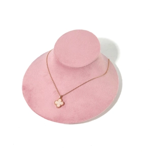 Detail of rose gold clover necklace with white mother-of-pearl on pink velvet display