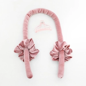Detail van de roze fluwelen haarkrulset zonder hitte met twee scrunchies en een haarklem