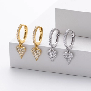 Macro view of gold and silver heart hoop earrings with micro-set cubic zirconia details