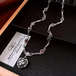 Retro silver necklace with multi-color gems and heart-shaped cross pendant in a jewelry box