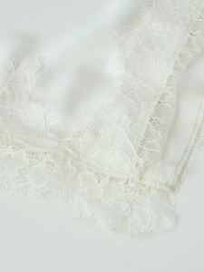 Détail d'une robe en satin blanc avec bordure en dentelle de cils et texture soyeuse