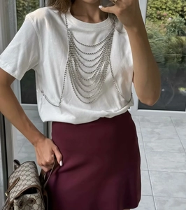 Détail de la chaîne de corps argentée multicouche avec strass sur un t-shirt blanc