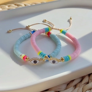 Detail of colorful Heishi bead bracelets featuring golden enamel Evil Eye charms and tassels