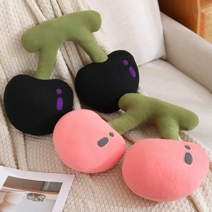 Plush cherry fruit pillows in black and pink colors on a cozy sofa setting