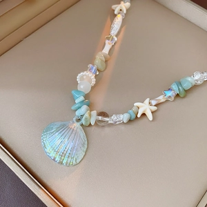 Macro detail of iridescent shell pendant and starfish beads in a jewelry box
