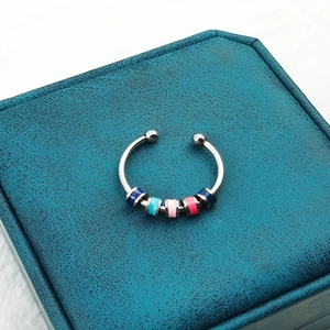 Detailed view of silver rotatable anxiety ring with five colorful enamel beads on jewelry box