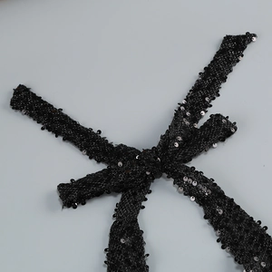 Macro detail of high-density black sequins stitched on a slim dress fabric band