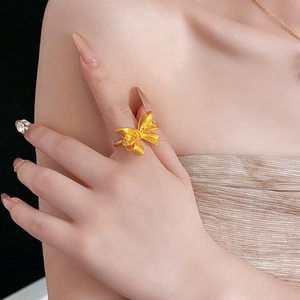 Detail shot of golden bow knot ring on model finger showing refined minimalist texture