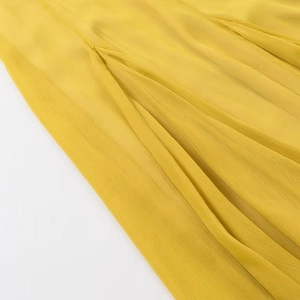 Makro-Detail von gelbem plissiertem Chiffon-Stoff mit weichem Fall und feiner Webung