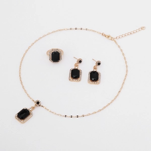 Detail of gold jewelry set featuring rectangular black gemstones and sparkling crystals
